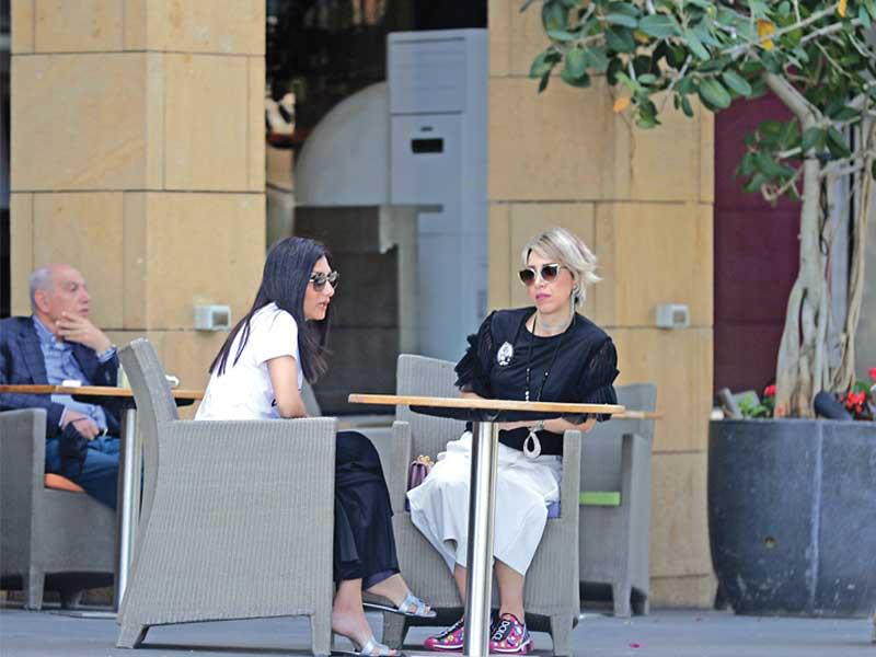 لبنانيتان تجلسان في مقهى ببيروت أمس قبل ساعات من سريان الحظر الشامل (أ ف ب)