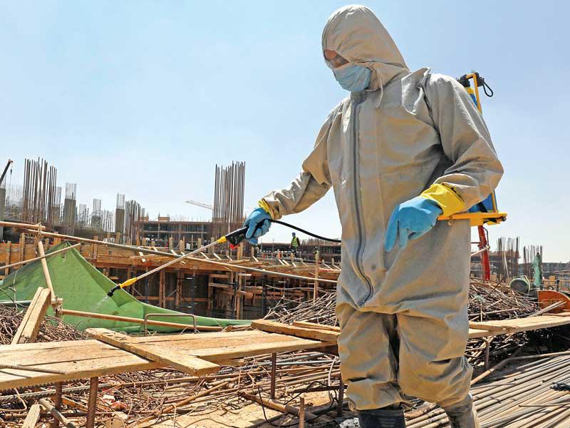 عامل مصري يعقم معدات البناء مع تواصل العمل في بناء العاصمة الإدارية (رويترز)