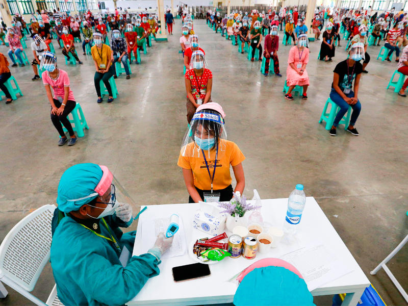 عناصر طبية من جيش ميانمار خلال عملية فحص جماعية أمس لعمال إحدى الشركات في مدينة يانغون  (أ ف ب)