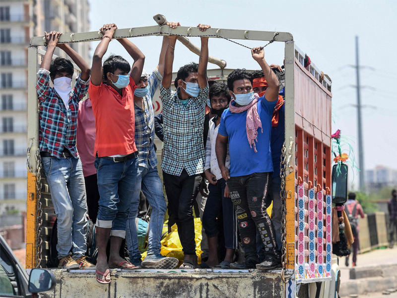 عمال هنود يتكدسون في شاحنة بنيودلهي للعودة إلى قراهم أمس (أ ف ب) 