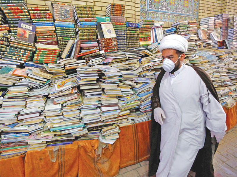 رجل دين شيعي يمر أمام بسطة تبيع الكتب الدينية في النجف أمس (رويترز)n