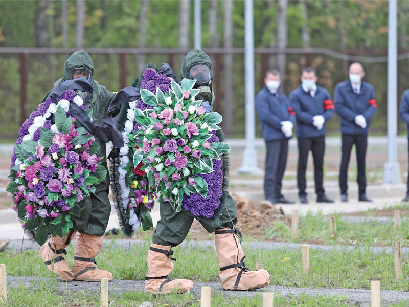 عاملان روسيان يحملان إكليلين من الزهور خلال دفن احد المتوفين بكورونا بموسكو قبل ايام     (رويترز)