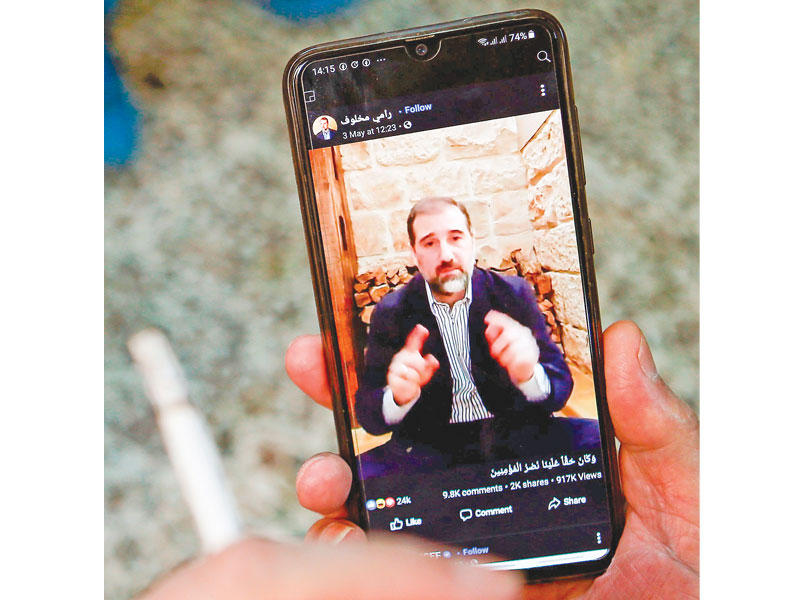 سوري يشاهد على هاتفه النقال أحد فيديوهات رامي مخلوف (أ ف ب)
