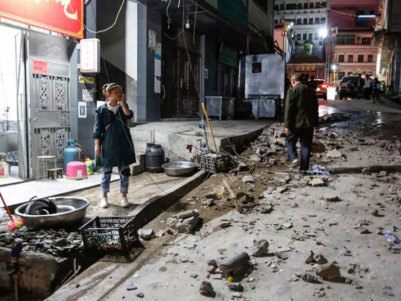 امرأة تقف خارج مطعم بعد الزلزال الذي ضرب منطقة كاوجي في الصين