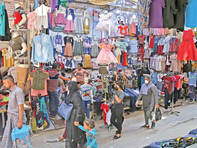 عراقيون بأحد أسواق بغداد أمس    (أ ف ب)