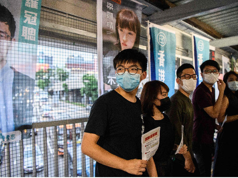 عضو حزب ديموسستو المؤيد للديمقراطية جوشوا وونغ وأعضاء حزبه الآخرون يوزعون منشورات ضد قانون الأمن القومي