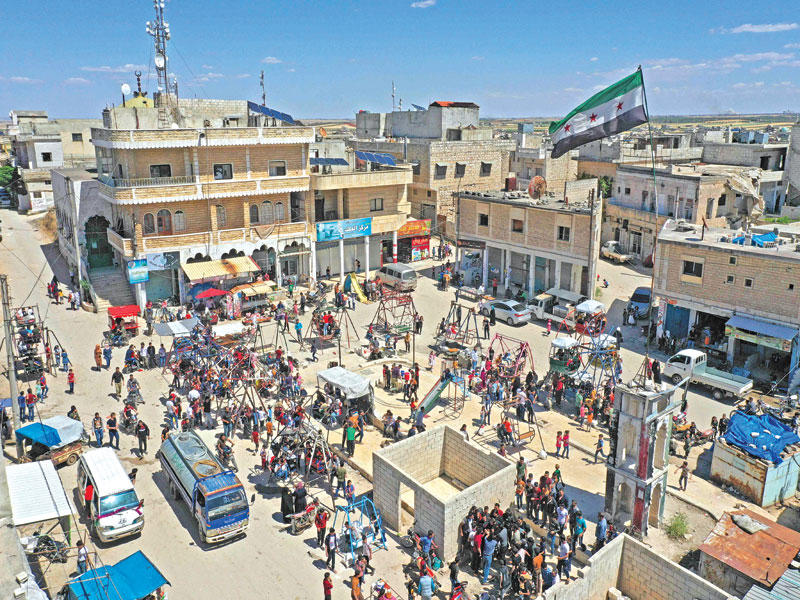 أطفال يلهون في ساحة بنش بإدلب إحدى البلدات القليلة التي لا تزال تحت سيطرة المجموعات المسلحة (أ ف ب) 