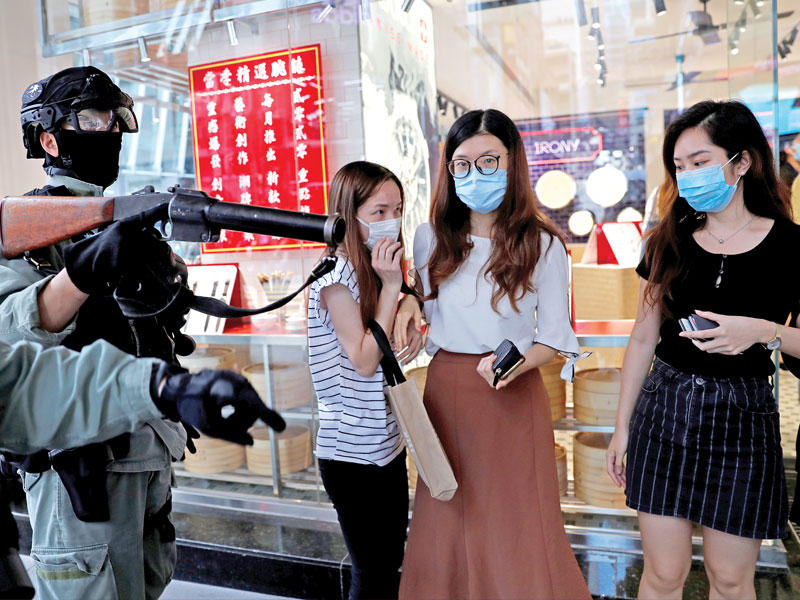 شرطي يفرق متظاهرين في هونغ كونغ امس (رويترز)