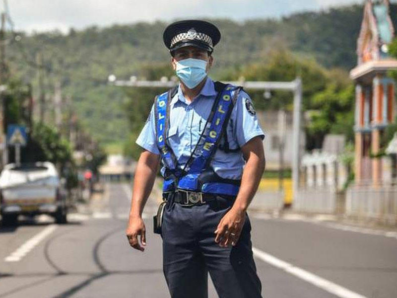 ضابط شرطة يرتدي قناعا عند نقطة تفتيش في منطقة فلاك موريشيوس التي تخضع لحظر التجول