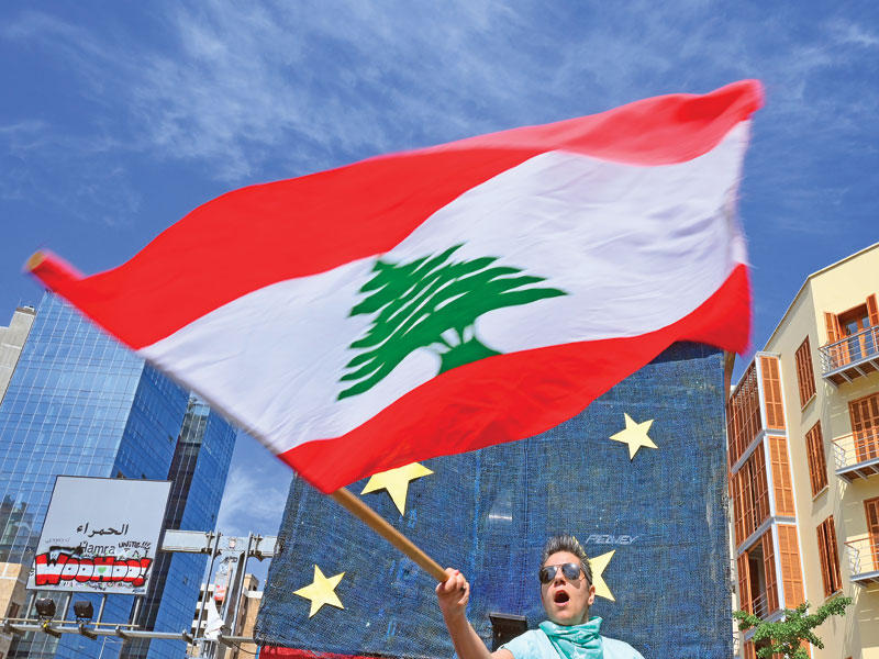 متظاهر يلوّح بالعلم اللبناني خلال وقفة احتجاجية على قانون العفو العام (اي بي ايه)