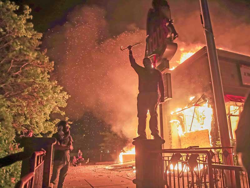 محتجون يحرقون مطعماً قرب مركز الشرطة في الدائرة الثالثة بمينيابوليس أمس الأول (إي بي أيه)