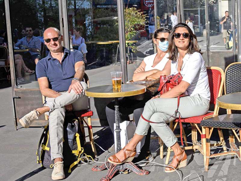 فرنسيون يستمتعون بالهواء الطلق في أحد مقاهي باريس (أ ف ب)