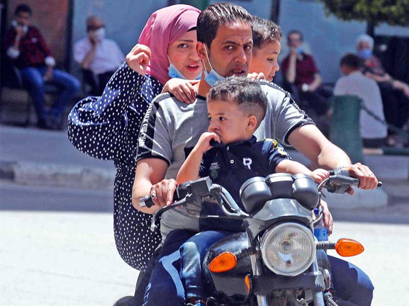  عائلة مصرية تضع الكمامات خلال تنقلها على دراجة نارية في القاهرة (رويترز)
