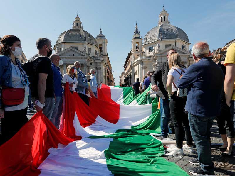 إيطاليون يحملون علماً عملاقاً خلال تظاهرة لليمين المتطرف بقيادة ماتيو سالفيني ضد قرارات الحكومة في روما أمس (رويترز)  