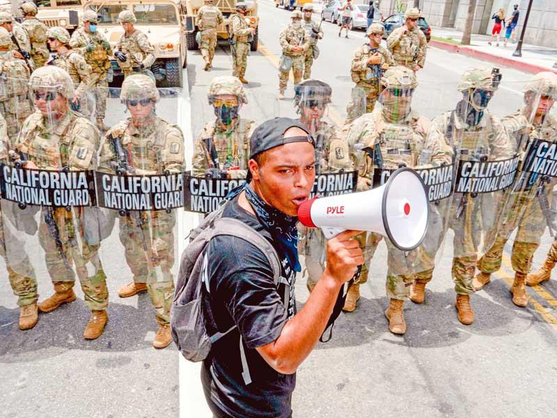 محتج أمام عناصر الحرس الوطني في لوس أنجلس أمس الأول (أف ب)