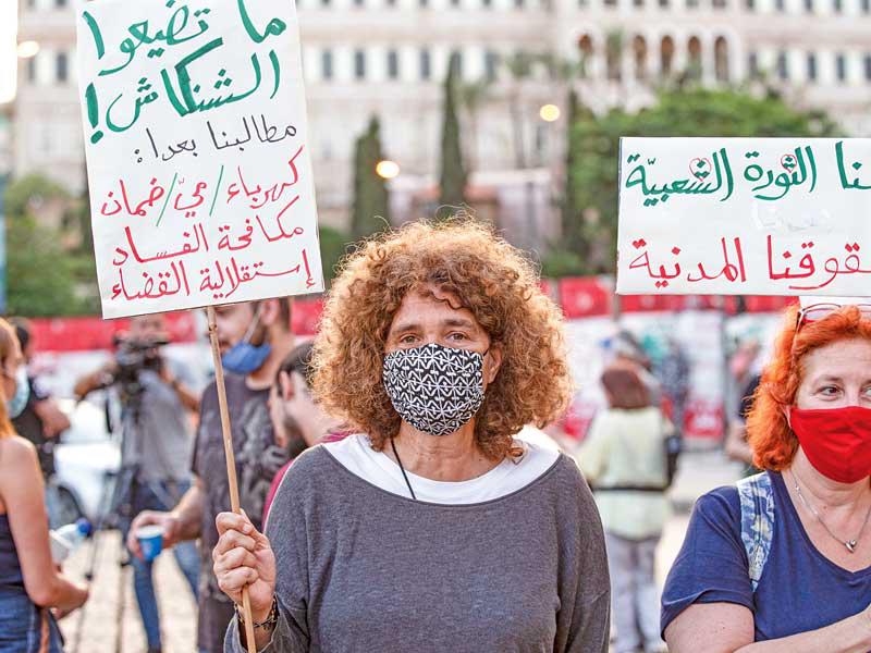 لبنانيتان تضعان كمامتين خلال تظاهرة  مناهضة للحكومة في بيروت أمس الأول (اي بي ايه)