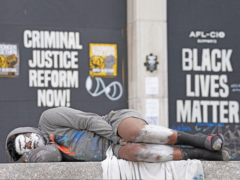 محتج نائم أمام لافتة «حياة السود مهمة سوداء» بالقرب من البيت الأبيض أمس (رويترز)