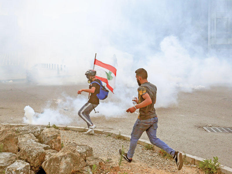 محتجان يتصديان لقنابل الغاز خلال تظاهرة معيشية في بيروت السبت الماضي (رويترز) 