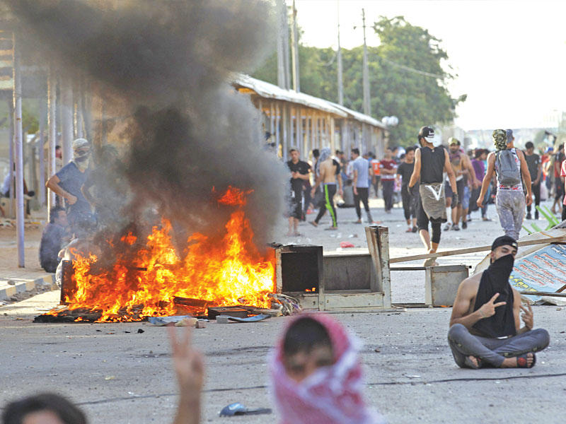 محتجون يحرقون إطارات لإغلاق طريق رئيسي في النجف الاثنين الماضي (رويترز)