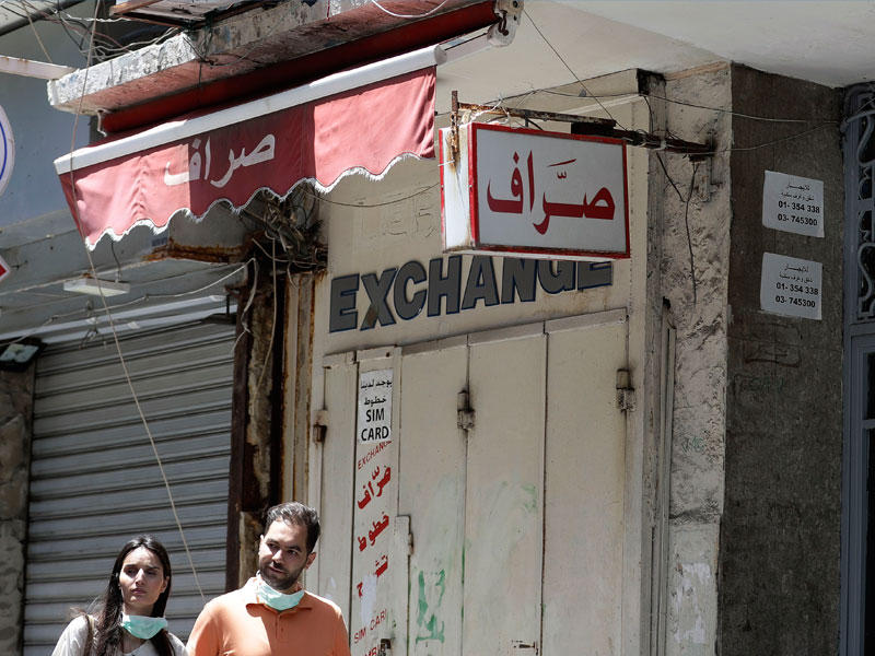 لبنانيان يمرّان أمام محلات صرافة مقفلة في بيروت أمس (أ ف ب)