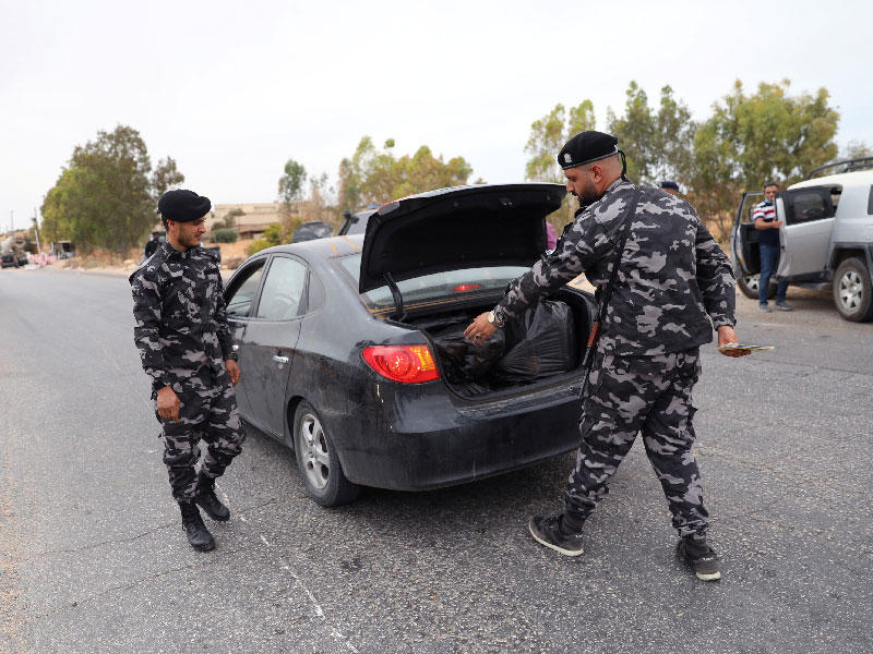 أفراد من قوات الأمن الموالية للحكومة الليبية المعترف بها دوليًا يقومون بفحص سيارة أثناء انتشار أمني في مدينة ترهونة ، ليبيا