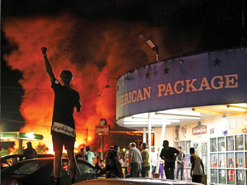 متظاهر قرب أحد المطاعم التي تمّ إحراقها في منطقة بروكز بأتلانتا مساء أمس الأول    (رويترز)