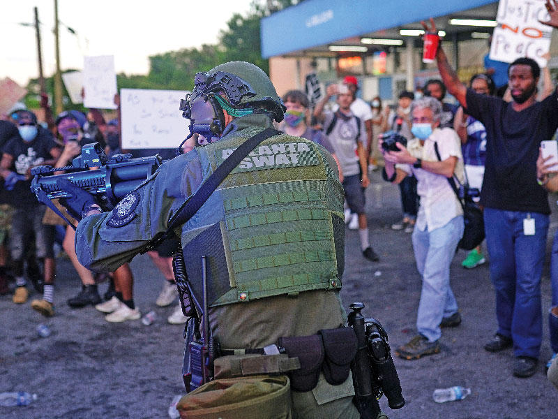 ضابط في قوات «سوات» الخاصة يواجه المحتجين في أتلانتا أمس الأول (رويترز)n