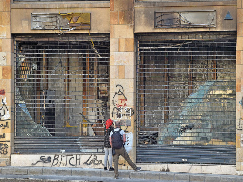 لبنانيان يعاينان الأضرار التي لحقت بأحد المحلات التجارية في وسط بيروت (اي بي ايه)