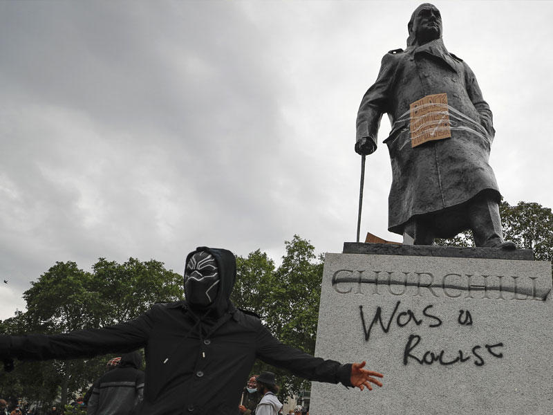 احد المتظاهرون بجوار تمثال ونستون تشرشل في ساحة البرلمان تظهر عليه اثار التشوية من المحتجين ضد العنصرية قبل أيام