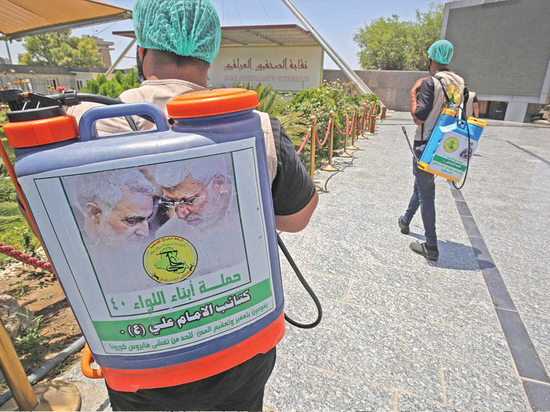 مناصرون لفصائل عراقية خلال حملة لتعقيم مواقع حيوية في بغداد (أ ف ب) 