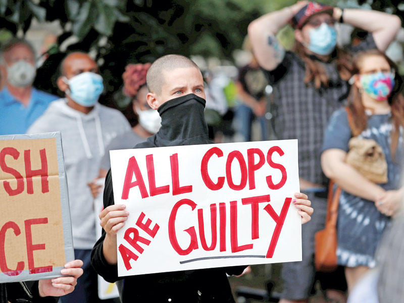 احد المتظاهرين يحمل لافته بأن جميع الشرطيين مذنبون أثار موجة غضب ضد العنصرية ووحشية الشرطة
