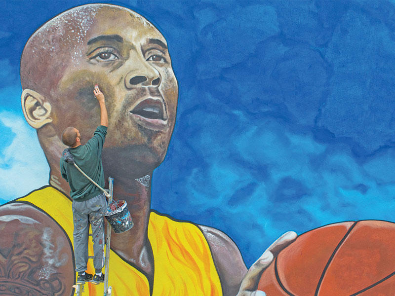 أحد الرسامين يكمل صورة حائط كبيرة للنجم الراحل كوبي براينت