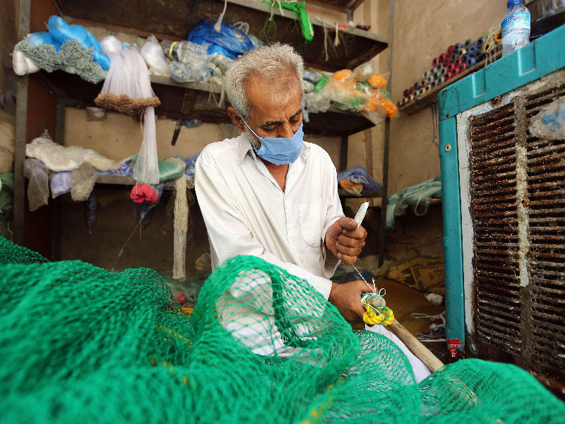 بائع أدوات لصيد الأسماك يحيك شبكة في النجف أمس (أ ف ب )