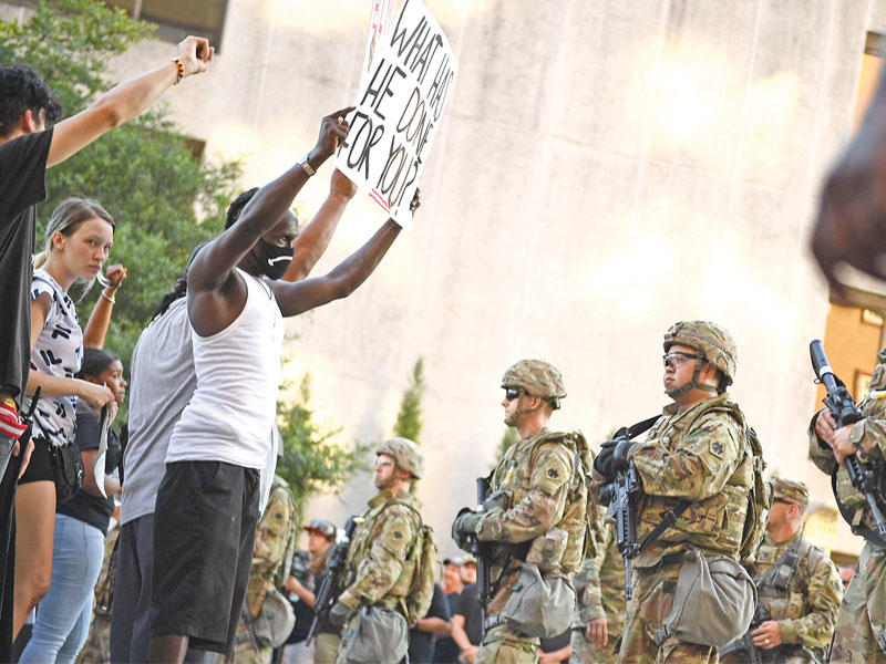 محتج بمواجهة عناصر «الحرس الوطني» على مدخل المجمع الذي استضاف لقاء تولسا السبت (أ ف ب) 