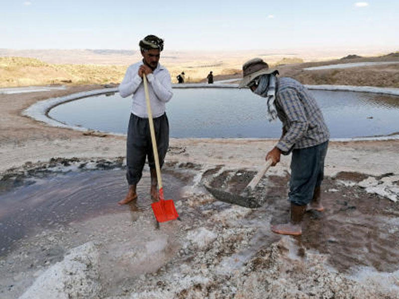 أكراد يستخرجون الملح من بحيرة في السليمانية بإقليم كردستان العراق المتاخم للحدود الإيرانية التركية (رويترز)