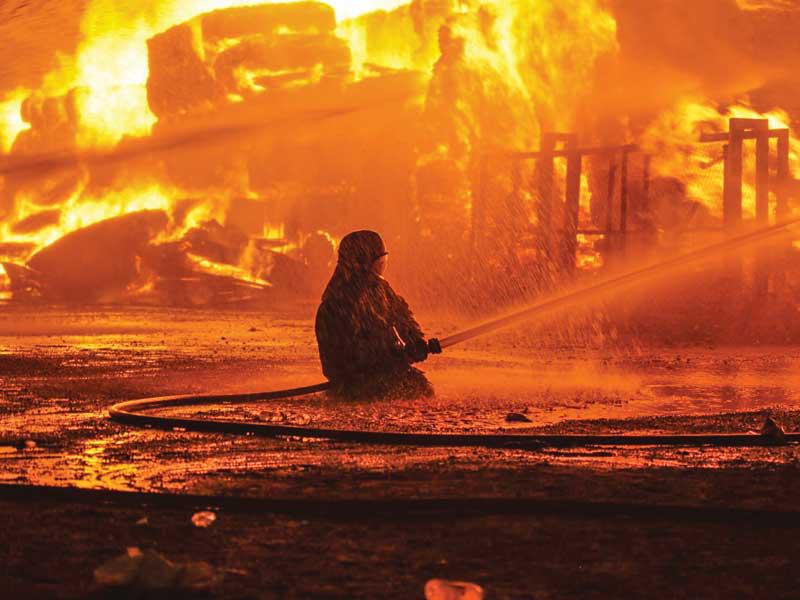 احد رجال الاطفاء يحارب نيران حريق ميناء عبدالله