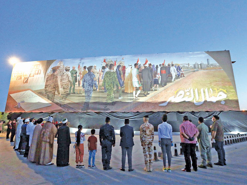 عراقيون أمام لوحة في موقع مقتل قاسم سليماني في بغداد قبل أيامt(إي بي ايه) 