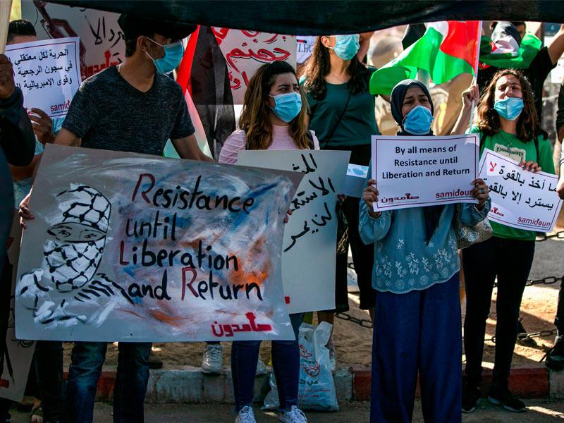 فلسطينيون يرتدون الأقنعة في مظاهرة ضد خطة إسرائيل لضم أجزاء من الضفة الغربية المحتلة ، في وسط مدينة رام الله في الضفة الغربية أمس      (AFP)