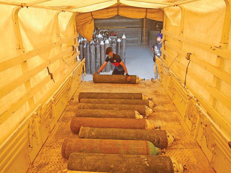 اسطوانات أكسجين في طريقها من مصنع في التاجي إلى المستشفيات العراقية المجابهة لكورونا  (أ ف ب)