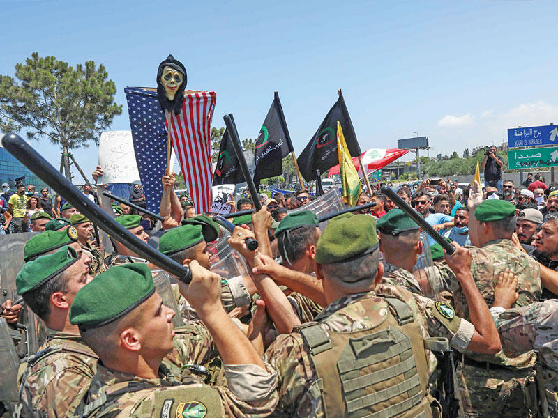 عناصر من الجيش تحاول إبعاد أنصار «حزب الله» الذين قطعوا طريق المطار احتجاجاً على زيارة ماكنزي (أ ف ب)