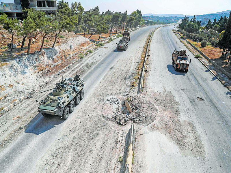 دوريتان روسية وتركية على طريق M4 الدولي حيث تبدو آثار قذيفة وسط الطريق (أ ف ب)