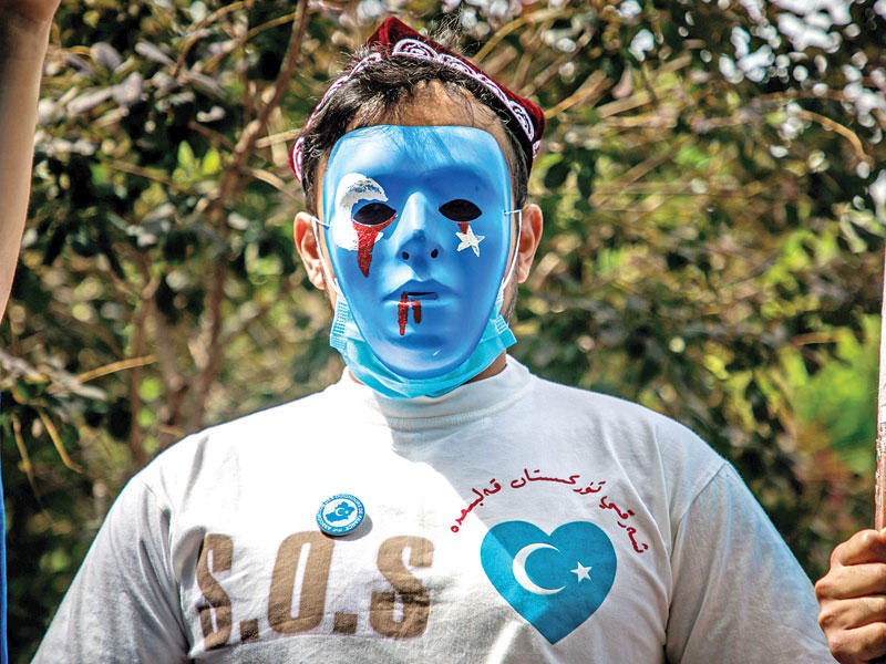 مقنّع خلال تجمع احتجاجي على سياسة بكين تجاه الإيغور في باريس أمس (إي بي أيه)