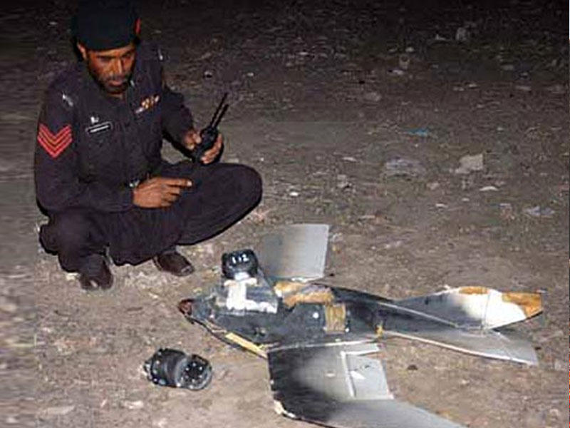 حطام طائرة بدون طيار بجانب احد عناصر الشرطة الباكستانية