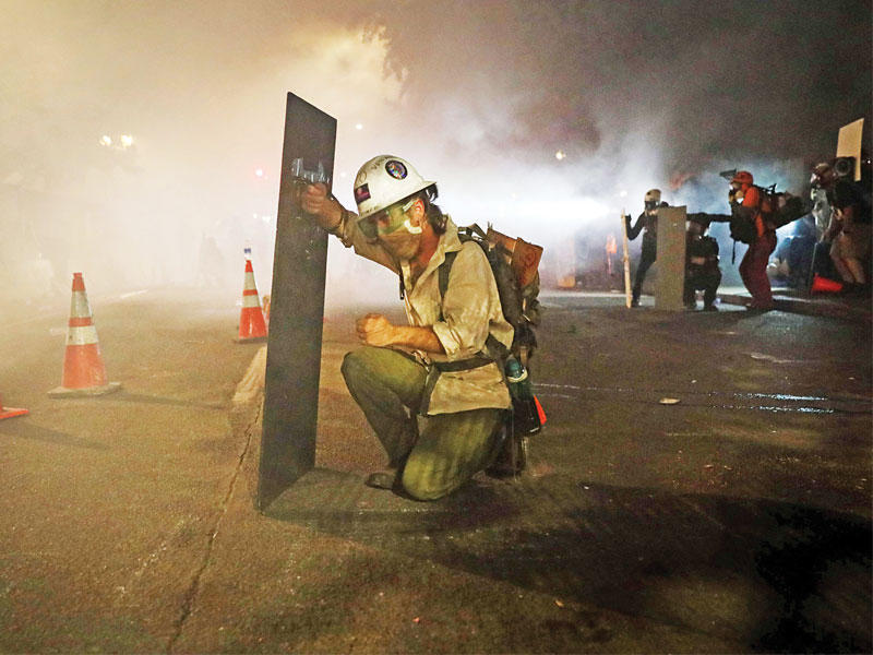 محتجة تحتمي بدرع من الشرطة في بوترلاند أمس الأول (أ ف ب)