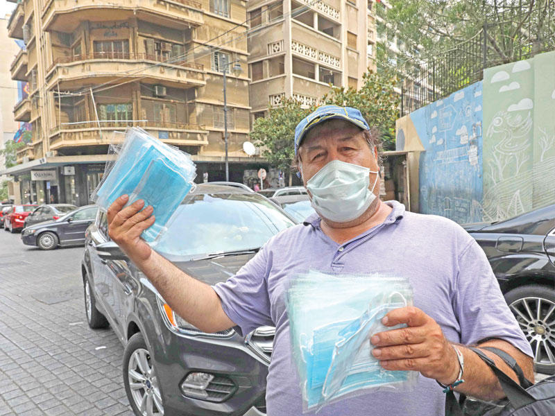 لبناني يبيع كمامات واقية في أحد شوارع بيروت أمس (أ ف ب)