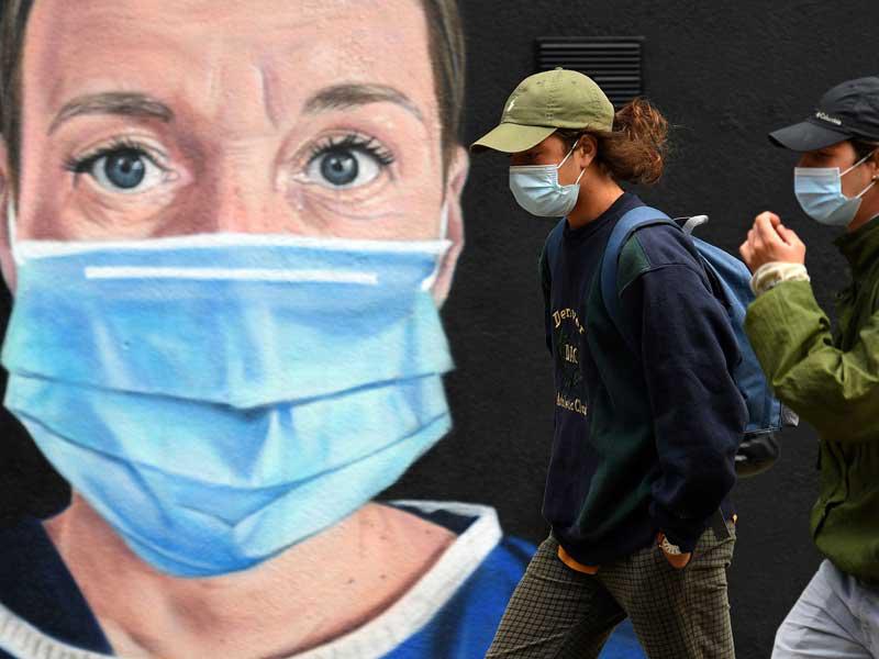 شابان بريطانيان يمرّان قرب رسم غرافيتي في مدينة مانشستر أمس (ا ف ب)