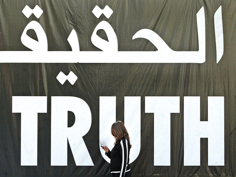 لبنانية تمر تحت شعار رُفِع ببيروت في 2005ـ يطالب بالحقيقة بشأن اغتيال الحريري (أ ف ب)n