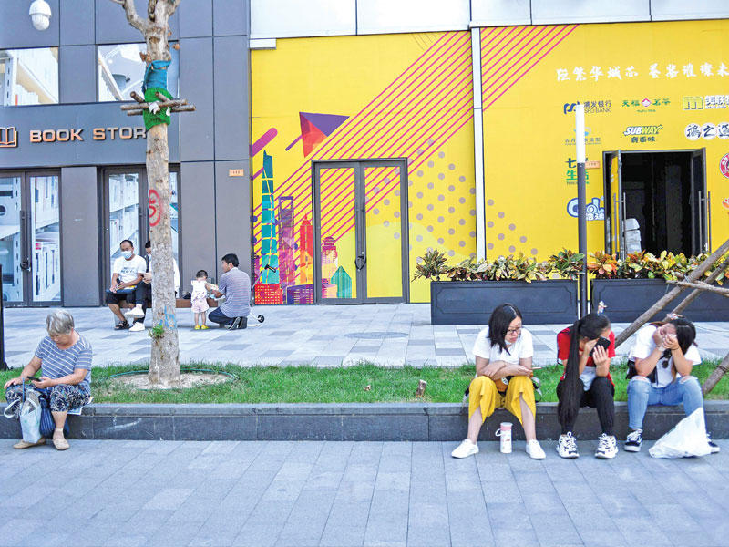 صينيون يجلسون خارج مركز تجاري في بكين أمس (أ ف ب)