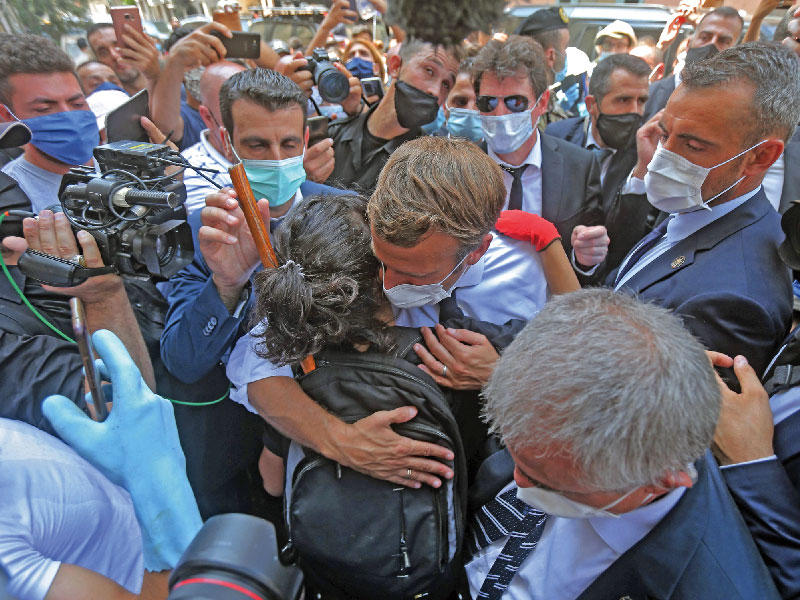 الرئيس الفرنسي إيمانويل ماكرون معانقاً فتاة وسط حشد في منطقة الجميزة بالأشرفية أمس (ا ف ب)