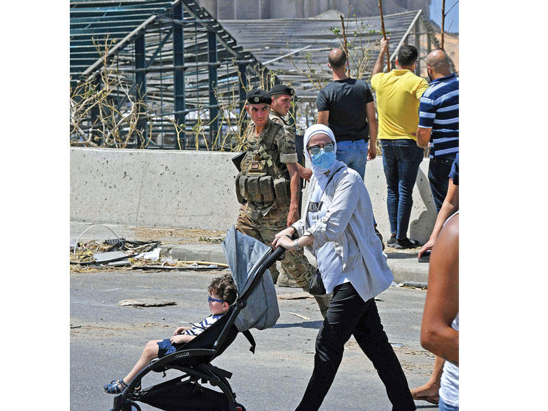 لبنانية تجر طفلها أمام مرفأ بيروت المدمر امس (أ  ف ب)